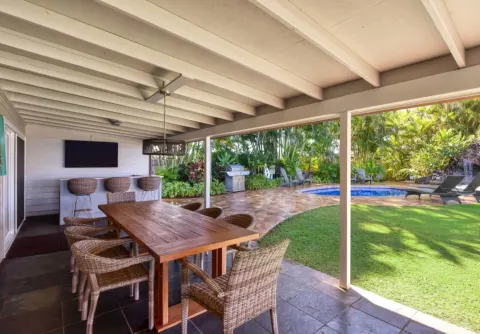 Covered patio with dining table, bar stools, lawn, and pool at Royal Lahaina Resort & Bungalows.