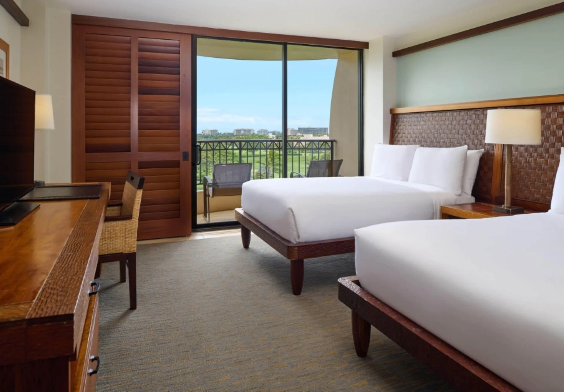 Guest room at Royal Lahaina Resort & Bungalows with two beds, wood desk, balcony, and garden view.