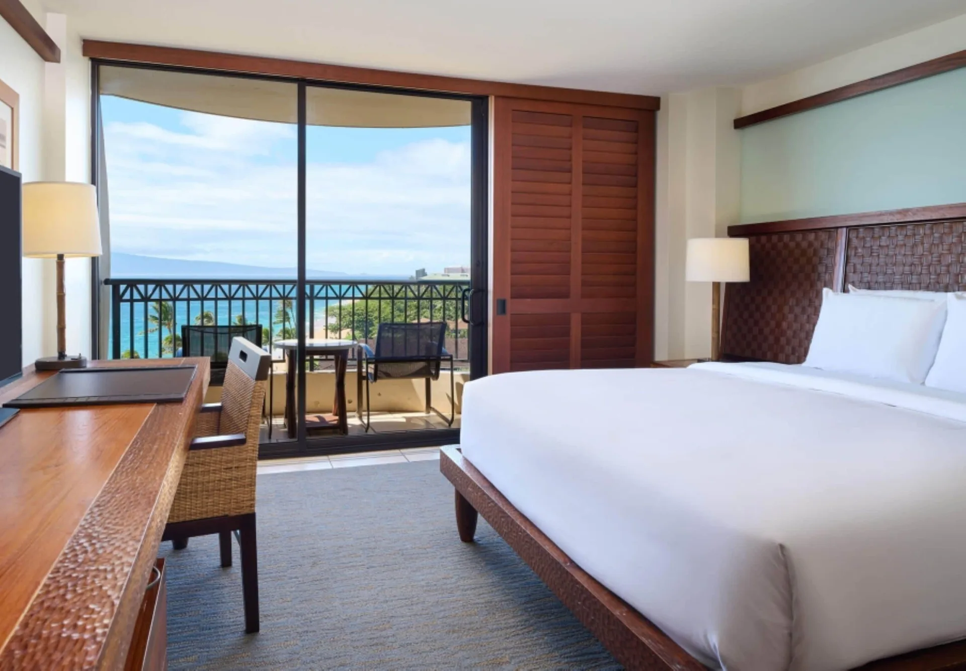 Guest room at Royal Lahaina Resort & Bungalows with king bed, desk, balcony seating, and ocean view.