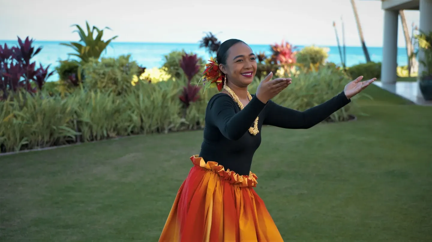 Hula dancer on the lawn with ocean behind at Royal Lahaina Resort & Bungalows.