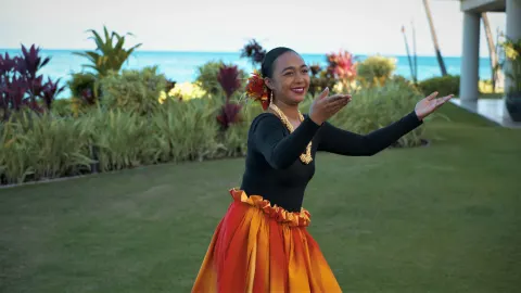 Hula dancer on the lawn with ocean behind at Royal Lahaina Resort & Bungalows.