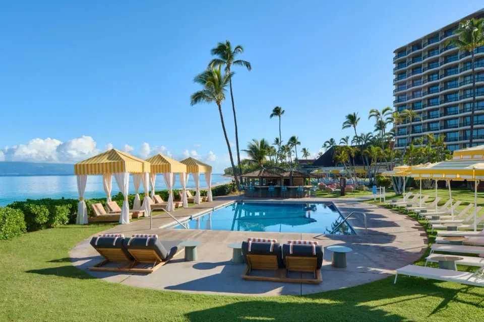 Oceanfront pool with yellow cabanas and tower at Royal Lahaina Resort & Bungalows.