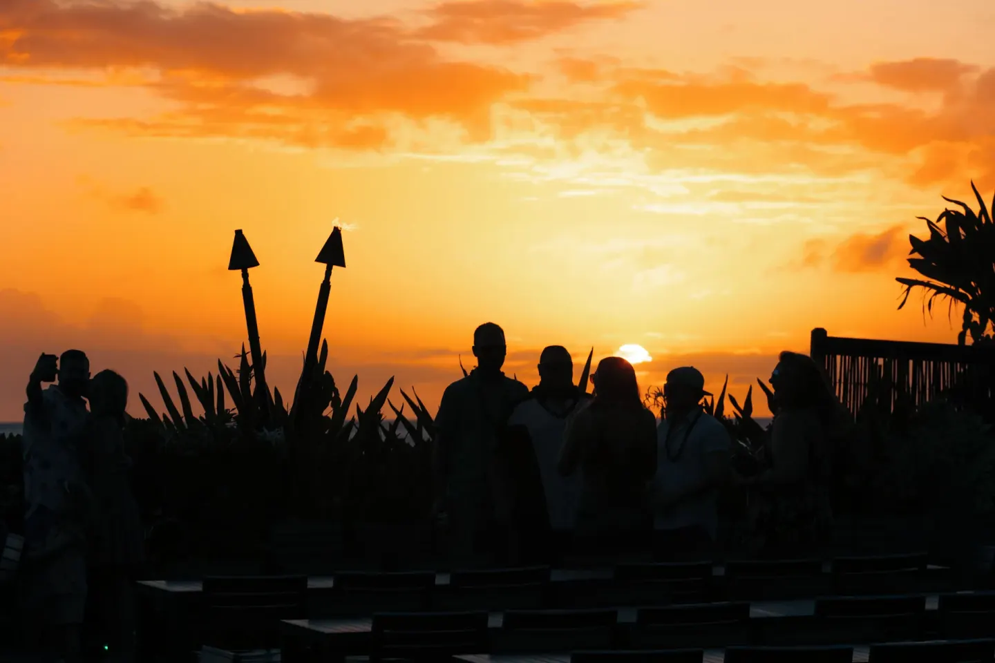 Sunset silhouettes of guests near torches at Royal Lahaina Resort & Bungalows.