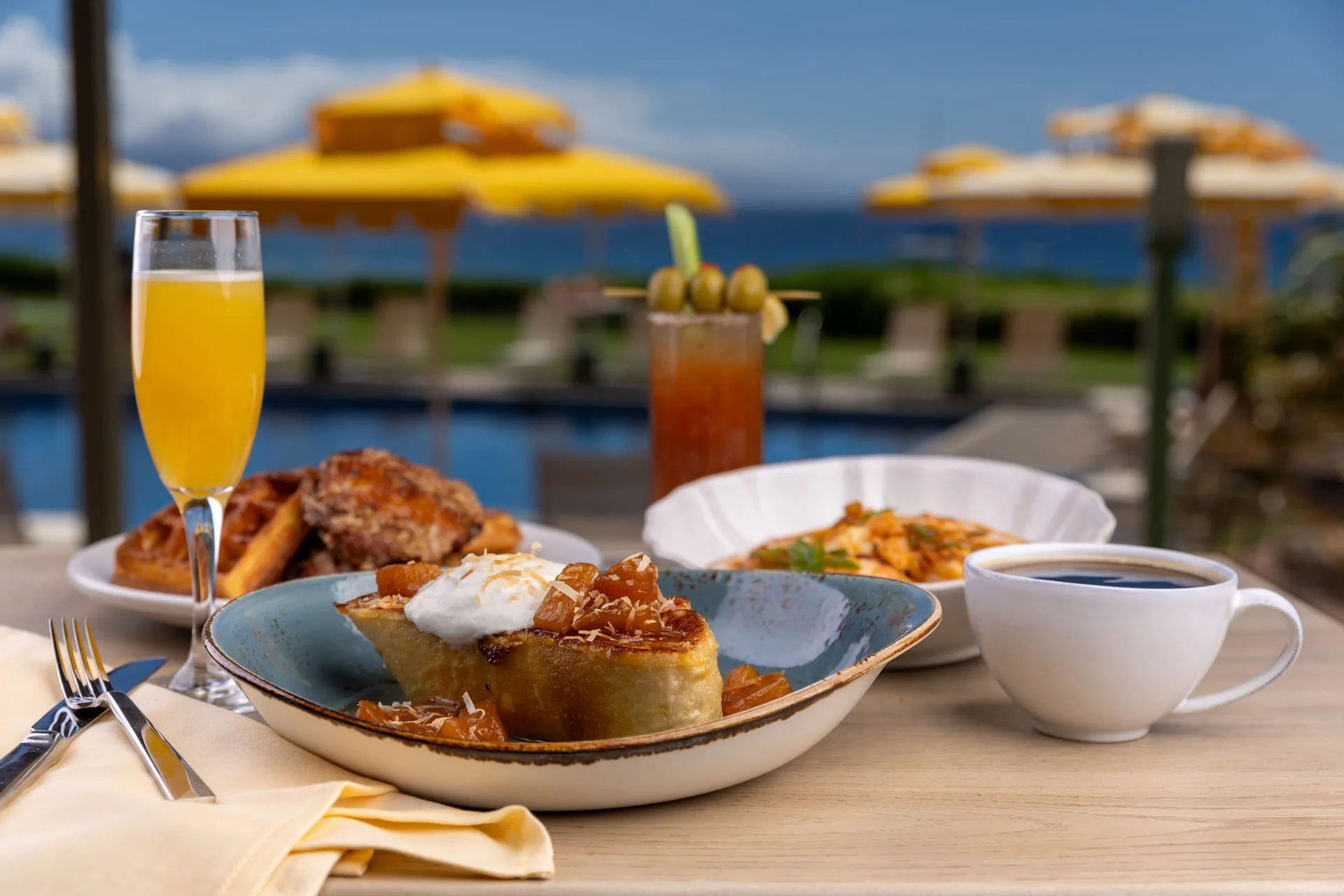 Breakfast plates, coffee, and drinks by the pool at Royal Lahaina Resort & Bungalows.