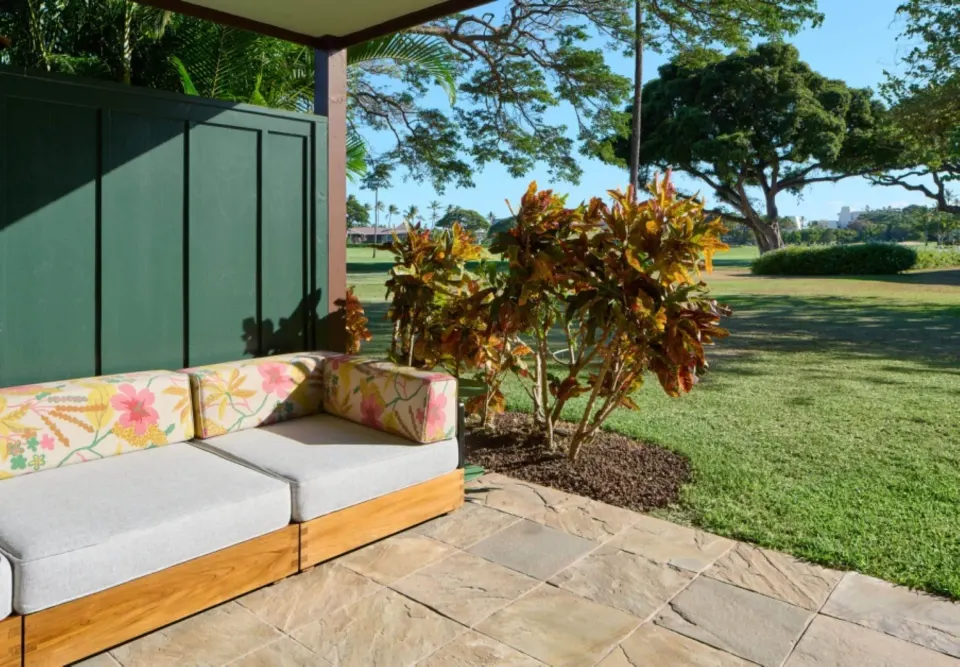 Bungalow Two lanai sofa beside lawn and tropical shrubs at Royal Lahaina Resort & Bungalows.