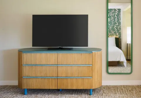 TV on a ribbed dresser with a wall mirror in an Oceanfront Bungalow Room at Royal Lahaina Resort & Bungalows.
