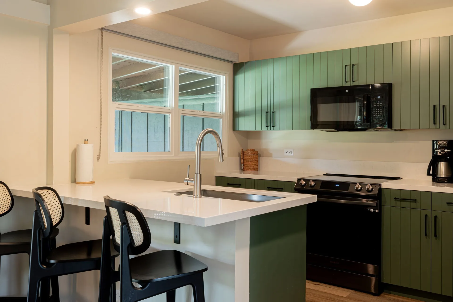 Kitchen with island sink, green cabinets, stove and bar seating at Royal Lahaina Resort & Bungalows.
