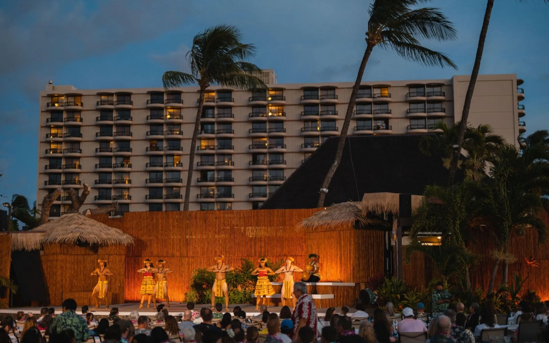 Outdoor luau performance with resort tower behind at Royal Lahaina Resort & Bungalows.