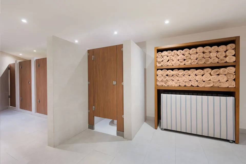 Changing area with wood stall doors and stacked towels at Royal Solaris Cancun.