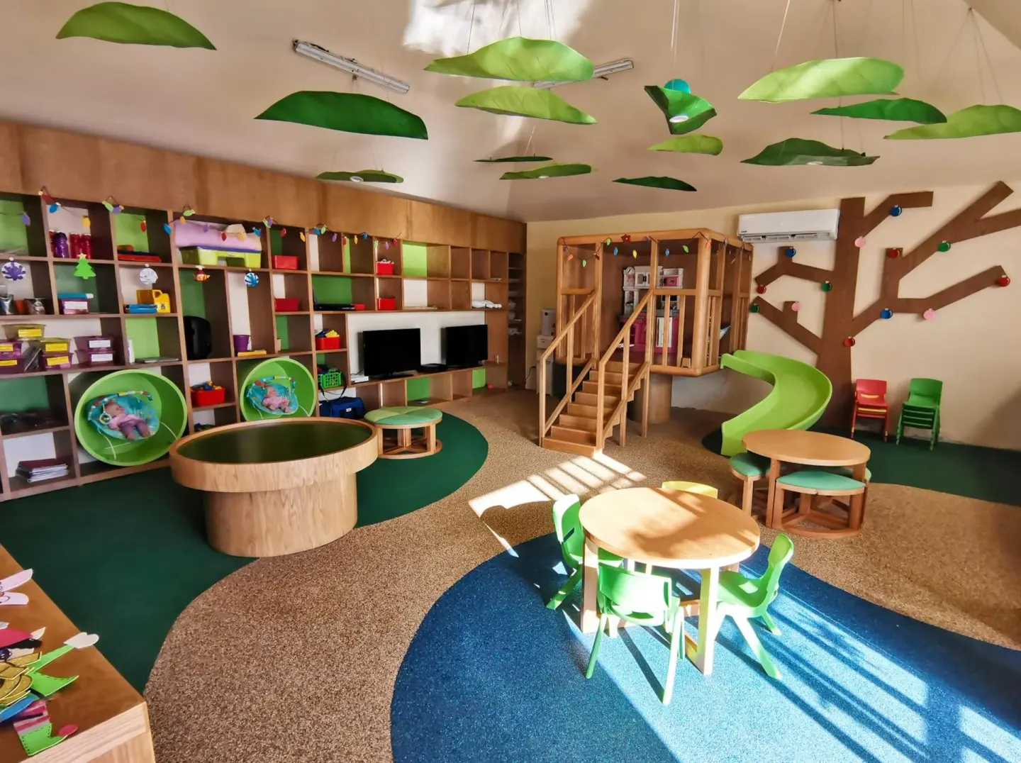 Kids club playroom with tables, shelves and green slide at Royal Solaris Cancun.