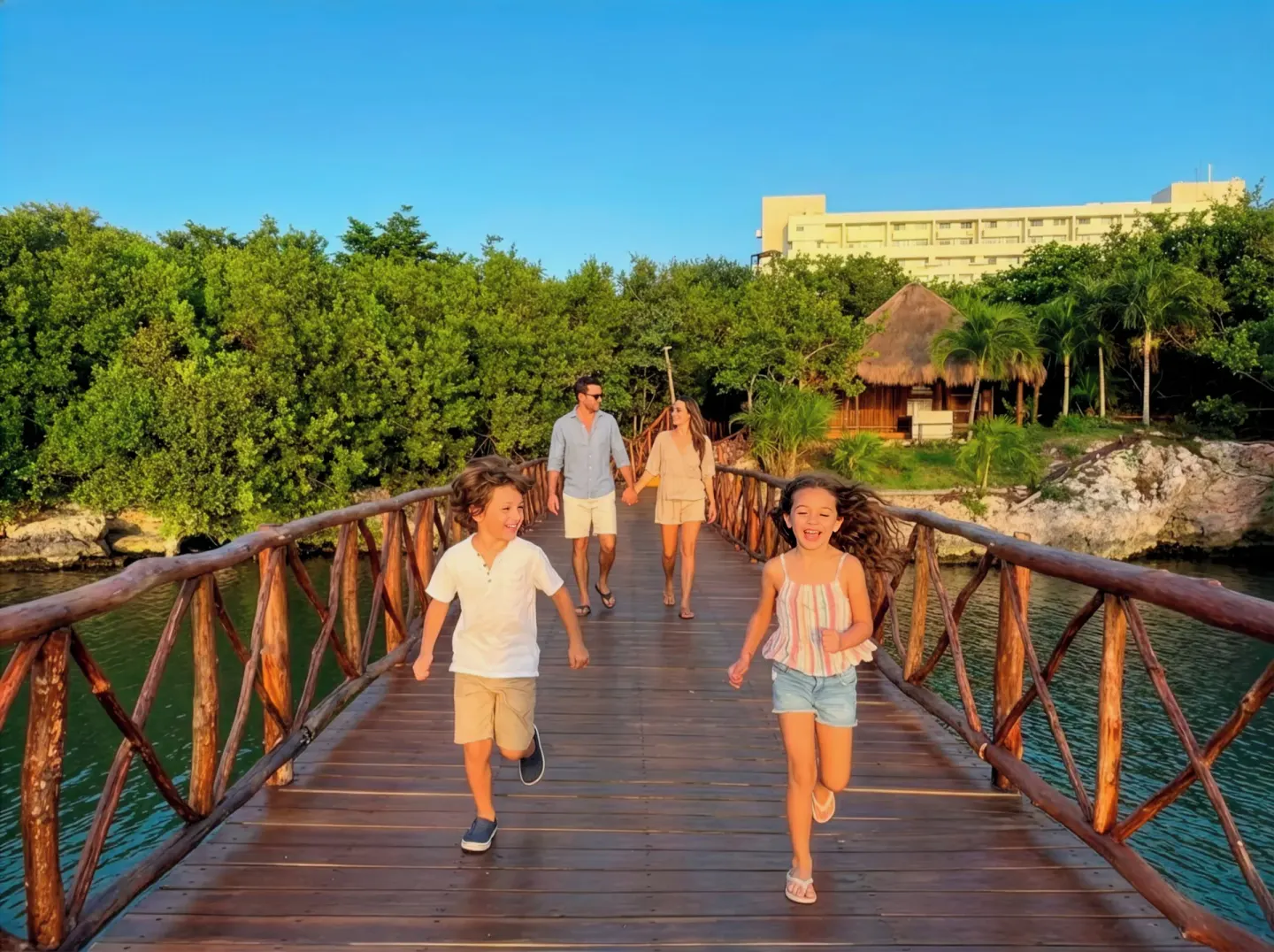 Family walks across a wooden lagoon bridge at Royal Solaris Cancun.