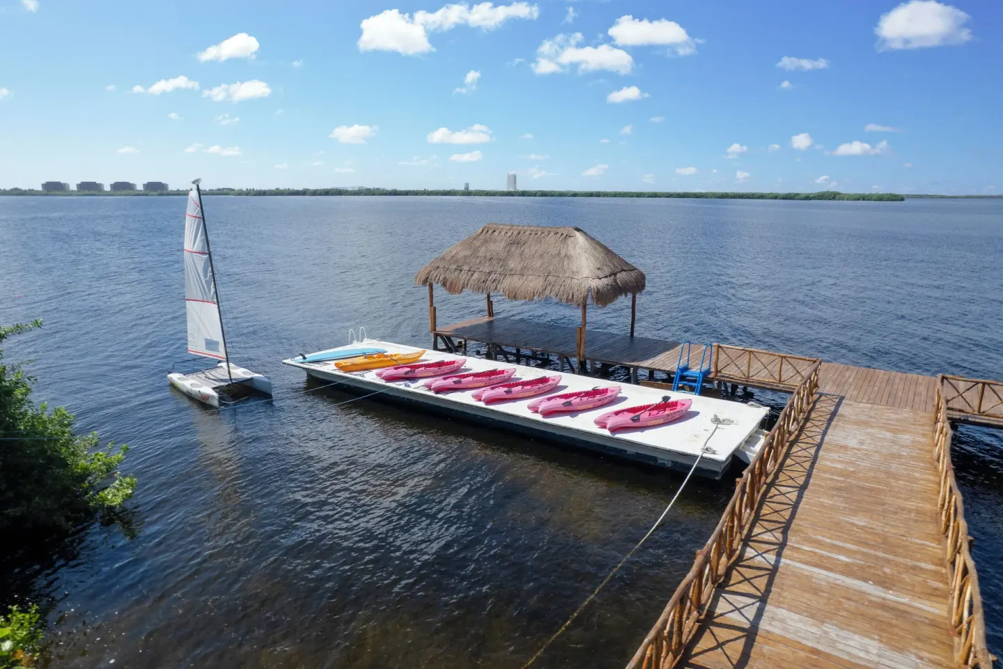 Lagoon dock with kayaks, a sailboat, and a thatched shelter at Royal Solaris Cancun.