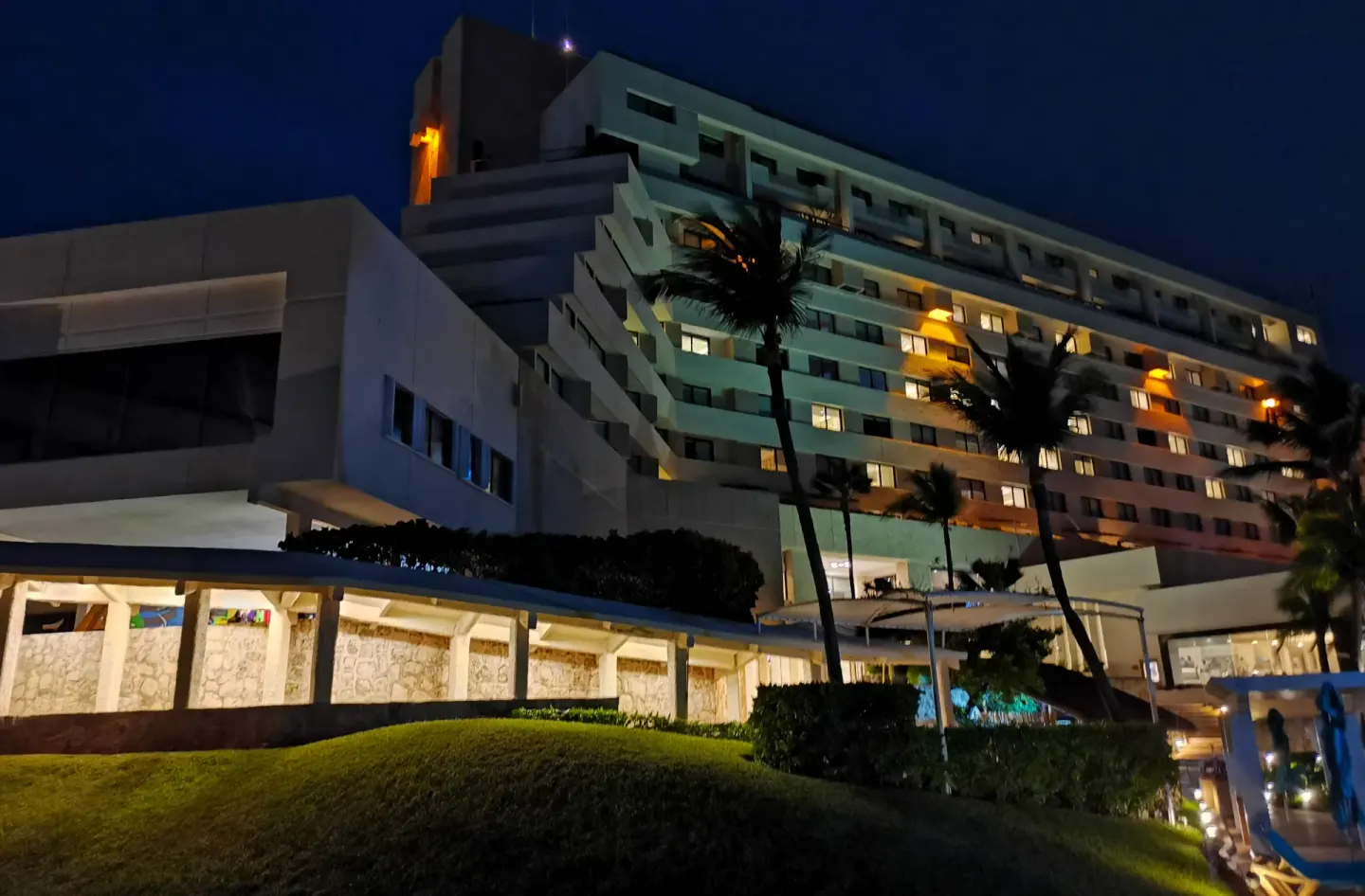 Night exterior of Royal Solaris Cancun with lit windows, palms, and landscaped grounds.