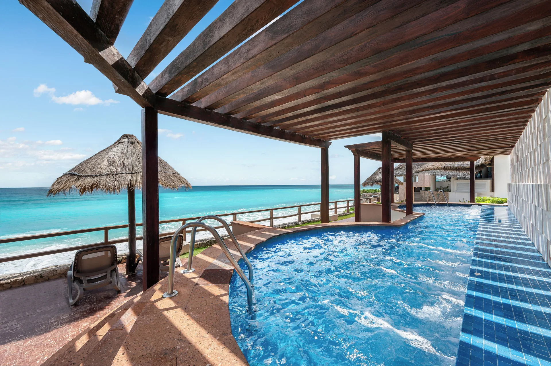 Oceanfront pool with pergola and palapa shade at Royal Solaris Cancun.