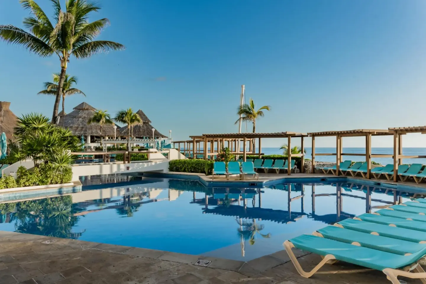 Main pool with turquoise loungers and ocean beyond at Royal Solaris Cancun.
