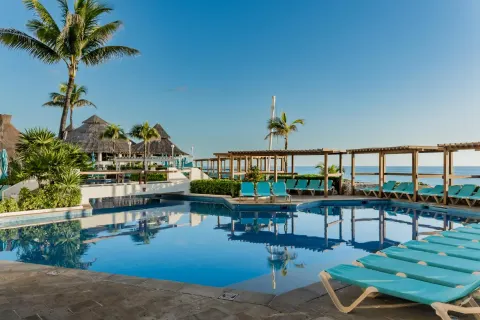 Main pool with turquoise loungers and ocean beyond at Royal Solaris Cancun.