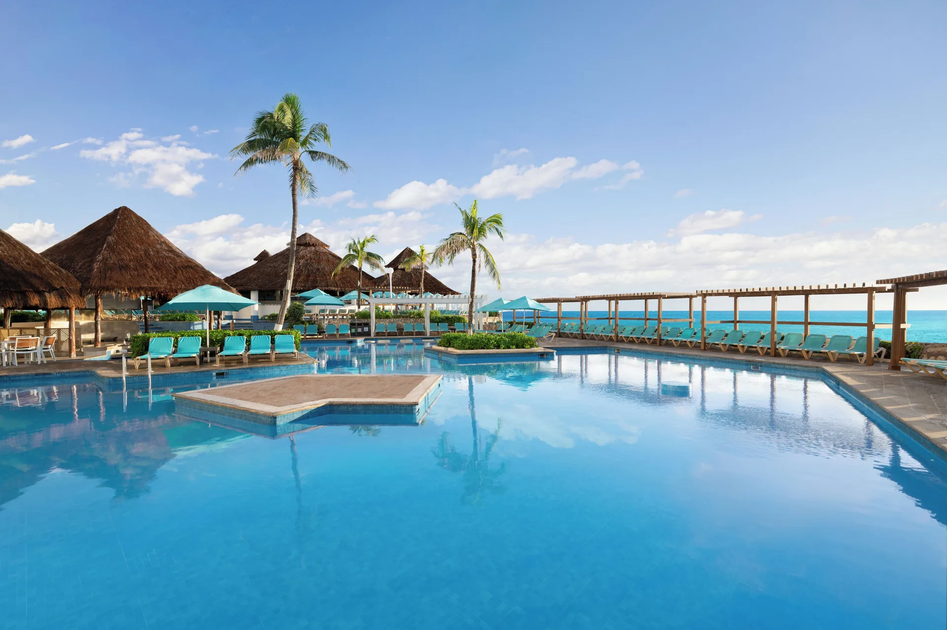 Oceanfront pool with palapas, loungers, and palm trees at Royal Solaris Cancun.