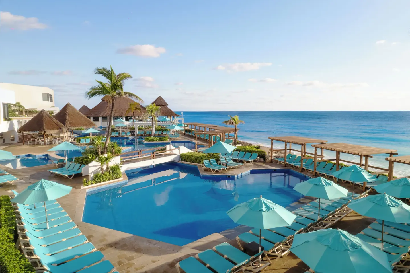 Oceanfront pool terrace at Royal Solaris Cancun with turquoise loungers and umbrellas.