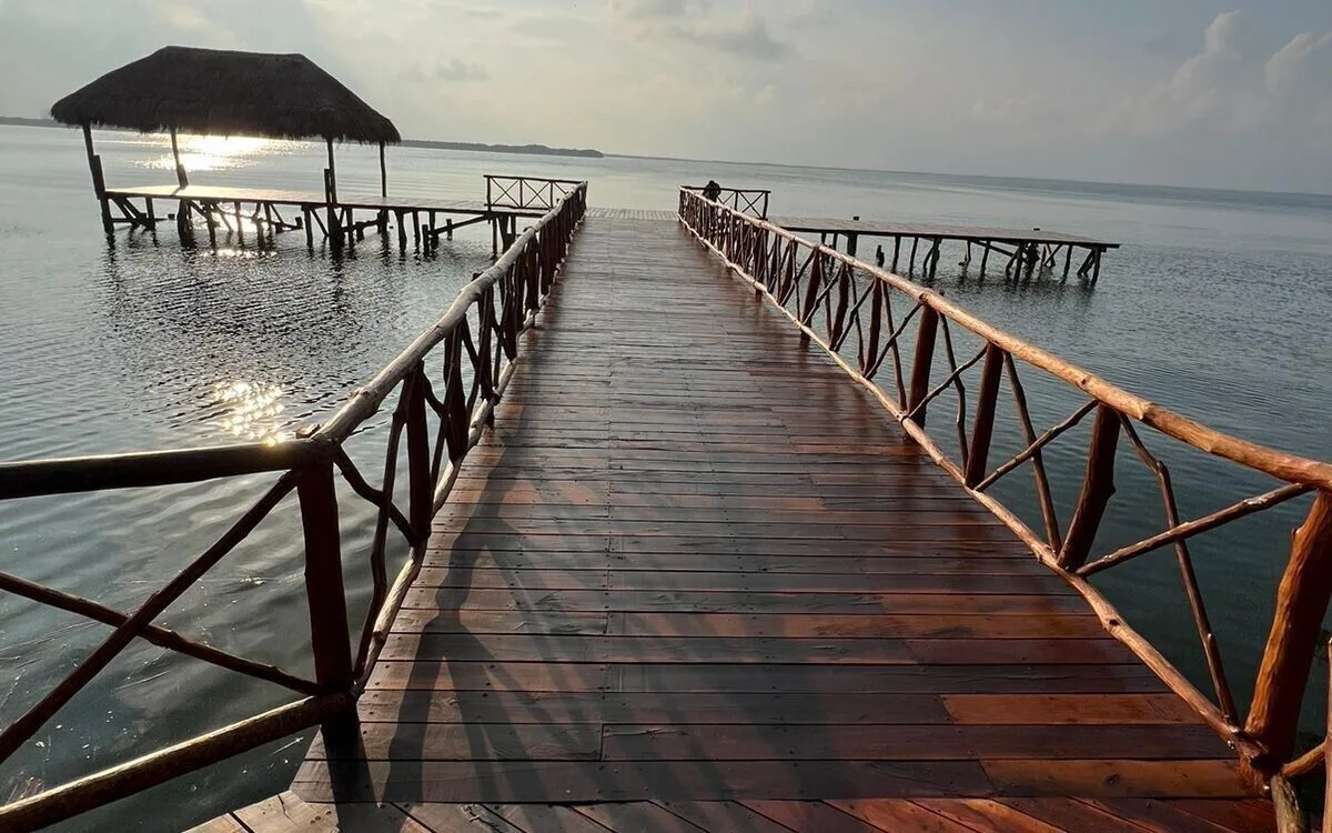 Wooden pier over calm water at sunrise or sunset at Royal Solaris Cancun.