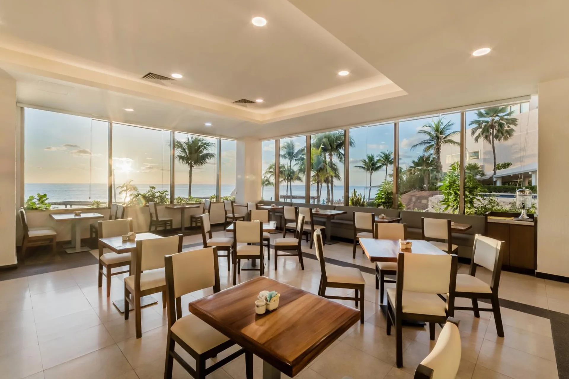Ocean-view dining room with tables and palm trees at Royal Solaris Cancun.
