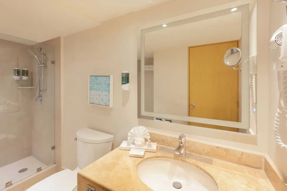 Deluxe Lagoon Room bathroom with vanity, toilet, and shower at Royal Solaris Cancun.
