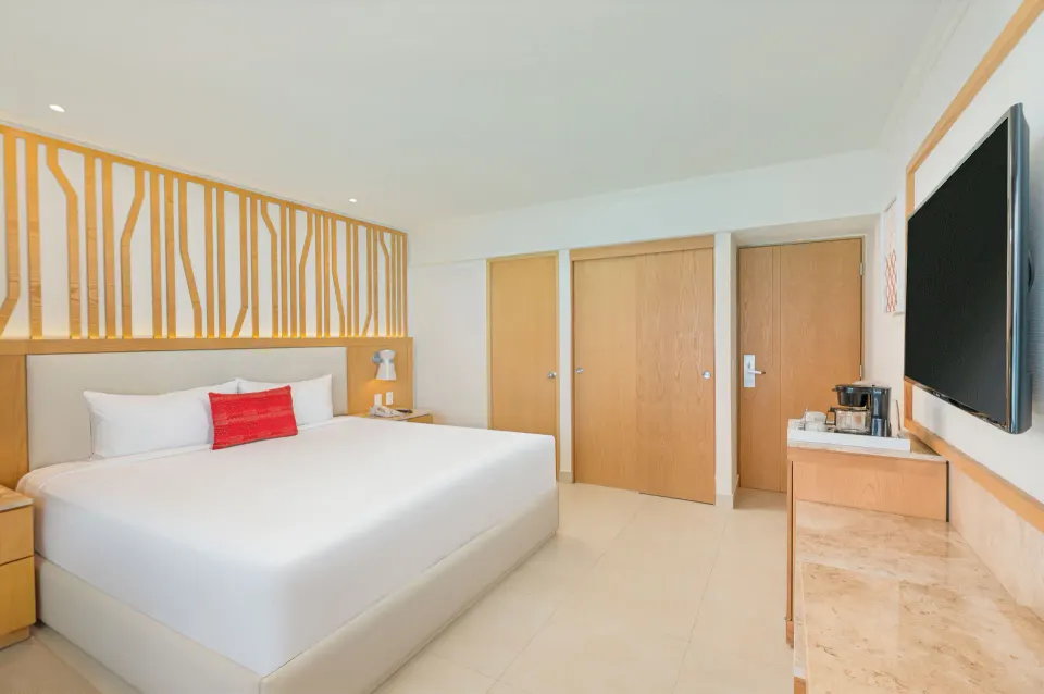 Deluxe king bed guest room with TV and wood accents at Royal Solaris Cancun.