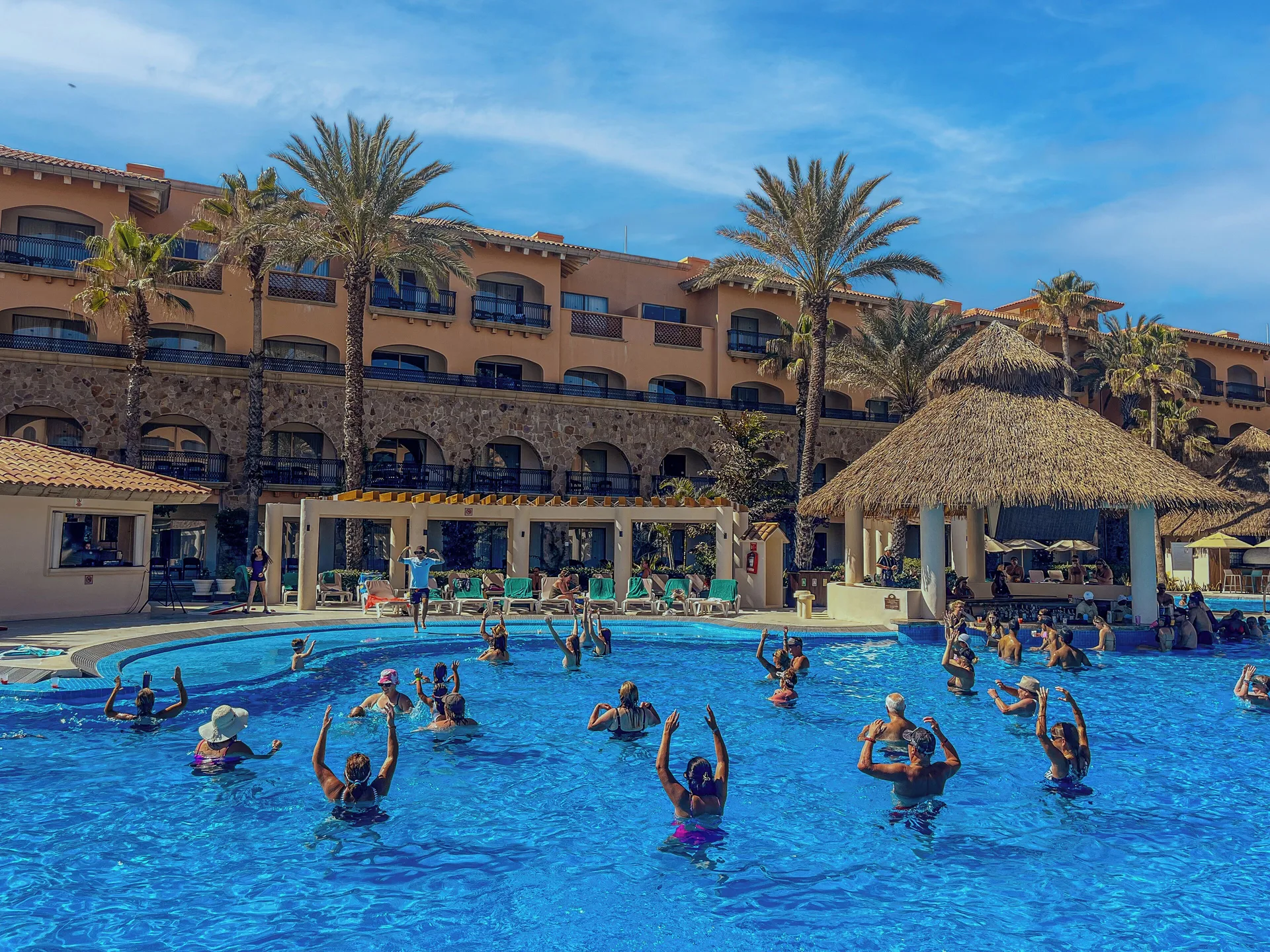 Guests join a pool activity beside a thatched pavilion at Royal Solaris Los Cabos & Spa.