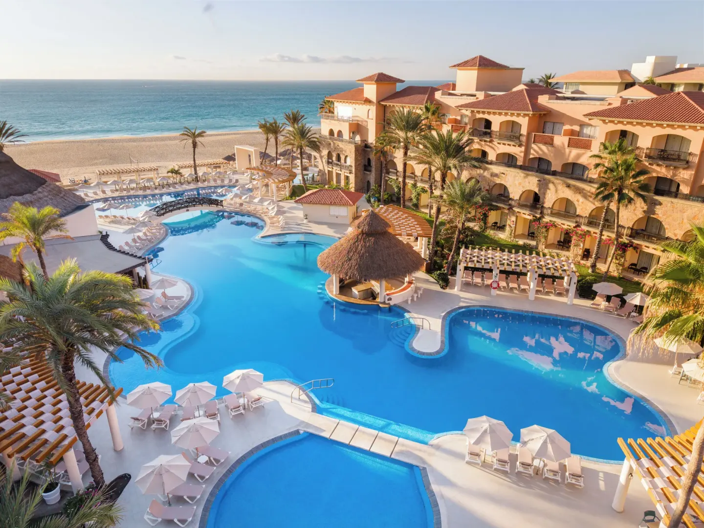 Resort pools, palms, guest buildings, and ocean at Royal Solaris Los Cabos & Spa.