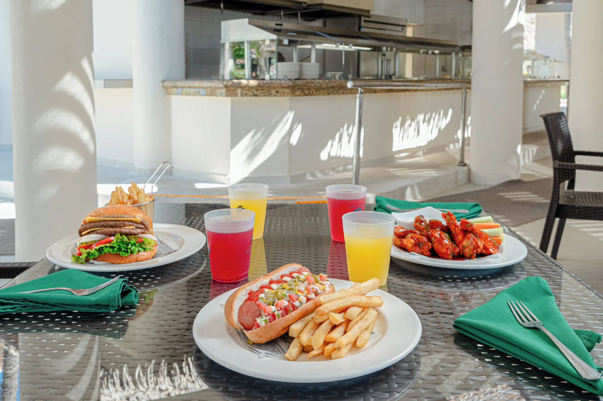 Hot dog, burger, wings, fries, and drinks on a table at Royal Solaris Los Cabos & Spa.