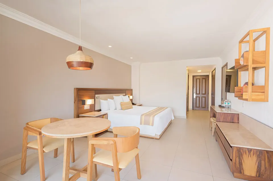 Deluxe Room king bed with round table and chairs at Royal Solaris Los Cabos & Spa.