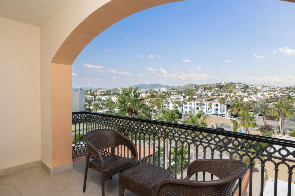 Deluxe Room balcony seating with town and palm views at Royal Solaris Los Cabos & Spa.