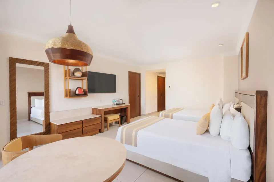 Deluxe Room with two beds, dining table, TV, and desk at Royal Solaris Los Cabos & Spa.