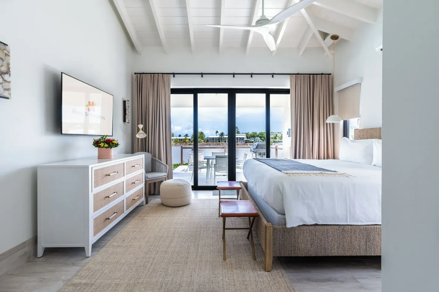 King bed guest room with TV, dresser, and balcony view at Royal St. Kitts Hotel.