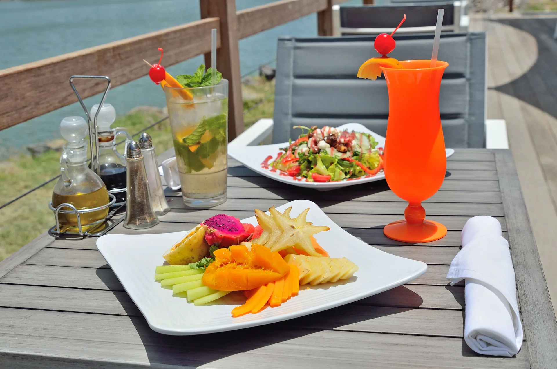 Fruit plate, salad, and colorful drinks on an outdoor table at Royal St. Kitts Hotel.