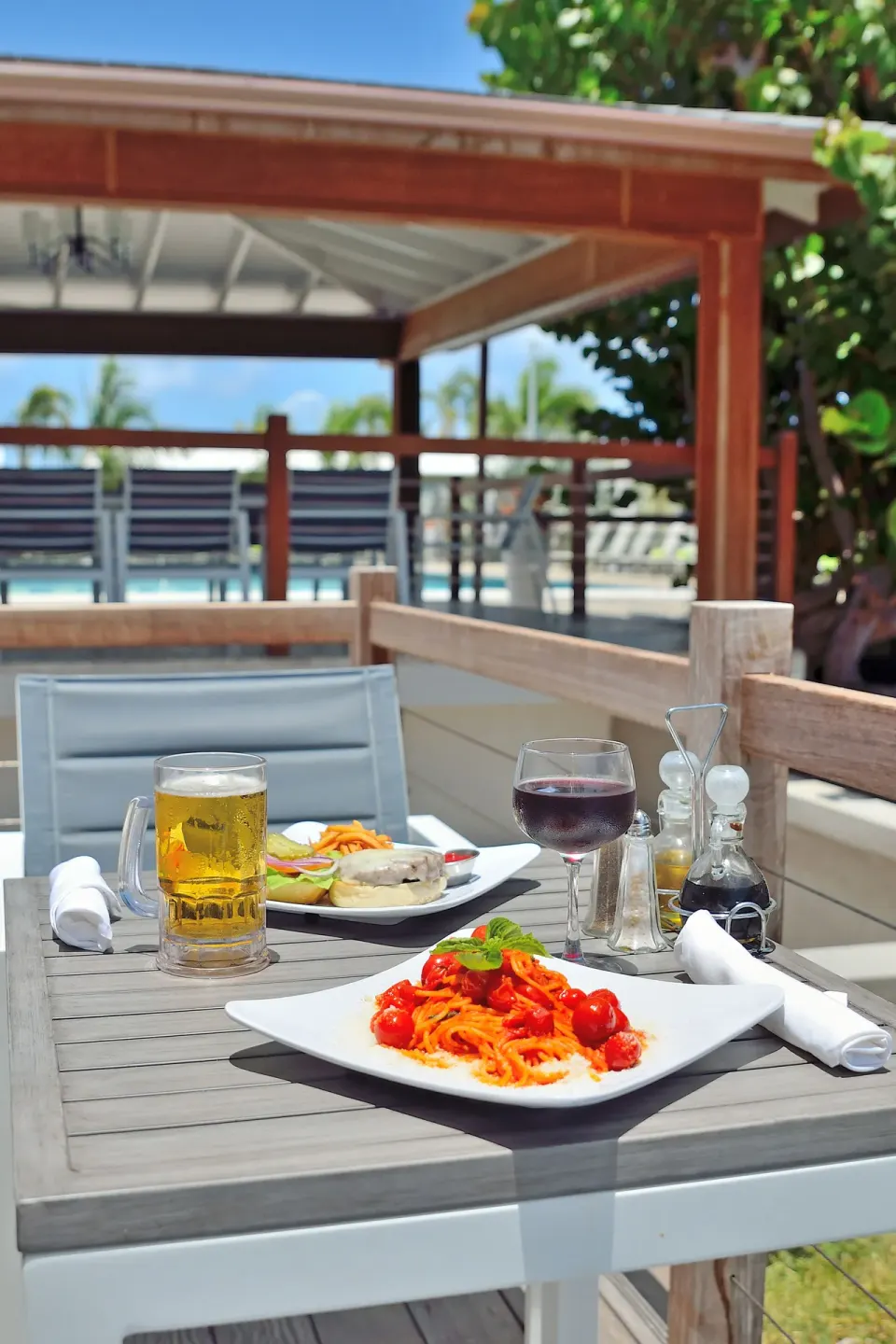 Outdoor table with pasta, drinks, and condiments at Royal St. Kitts Hotel.