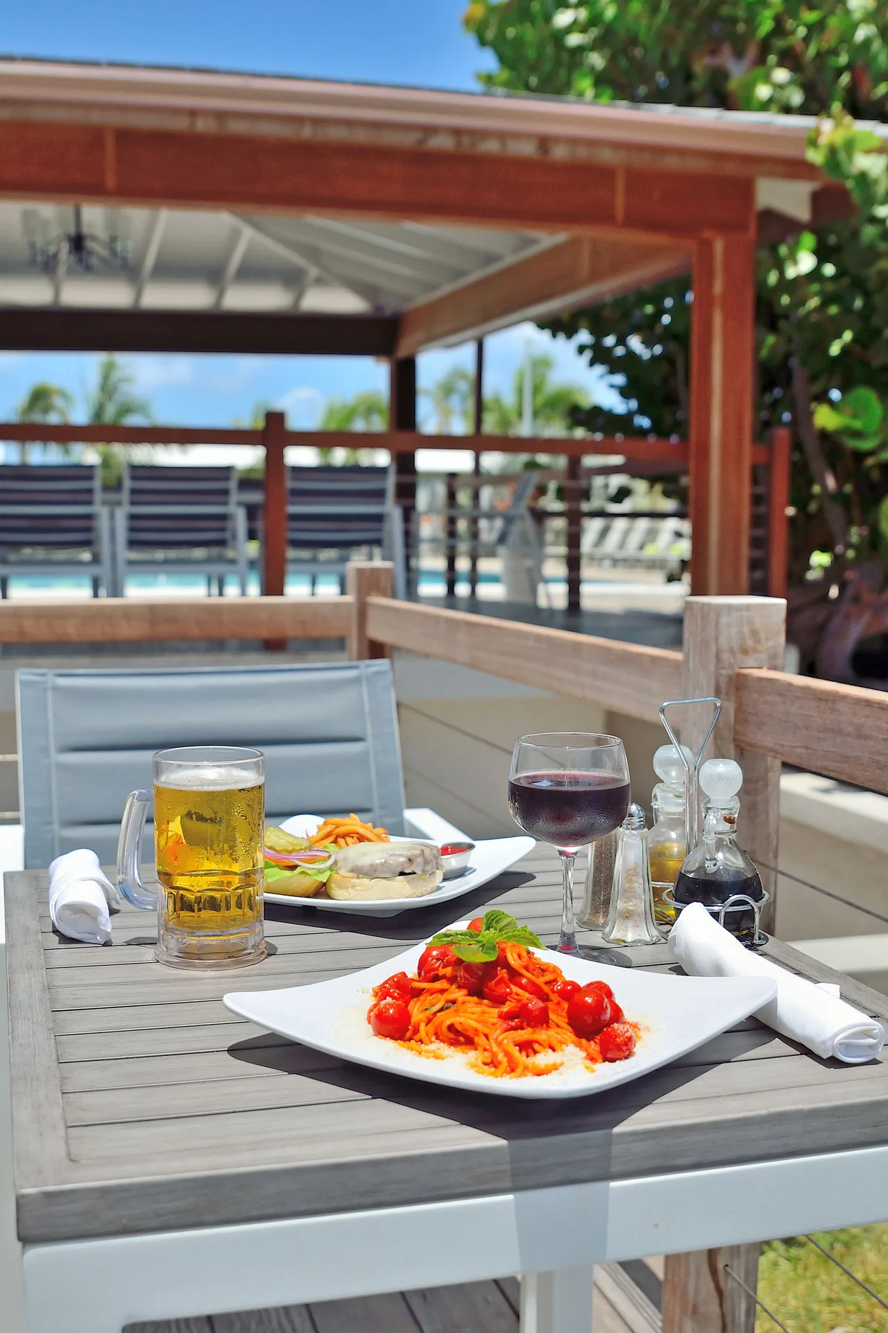 Outdoor table with pasta, drinks, and condiments at Royal St. Kitts Hotel.