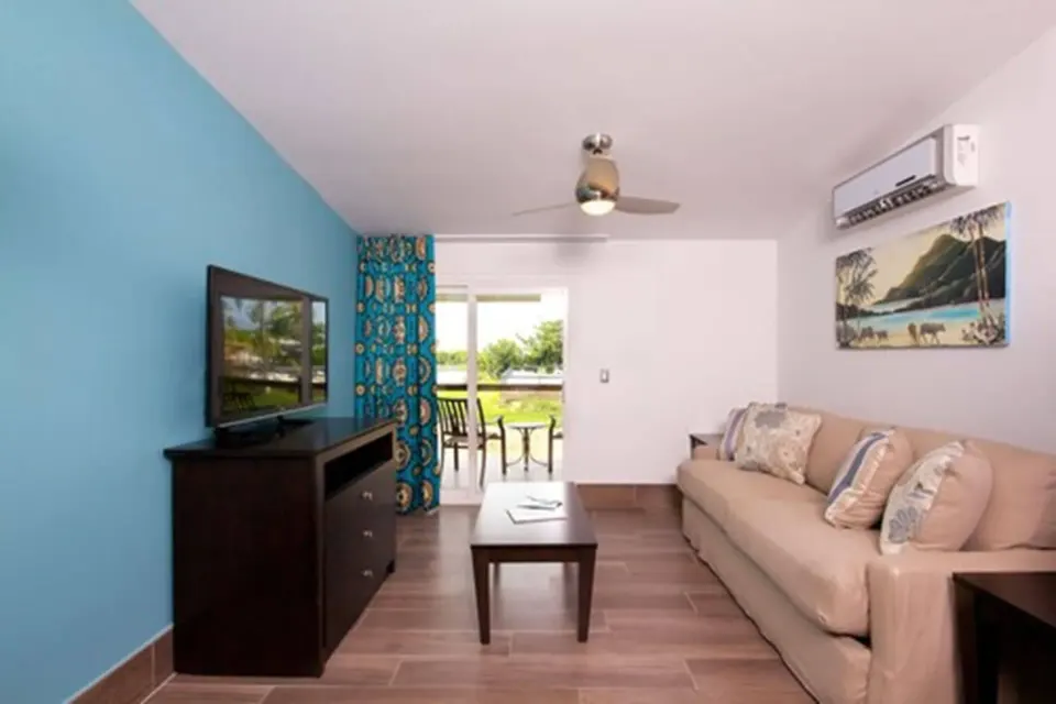 Premium Apartment 1 Bedroom living room with sofa, TV, and balcony at Royal St. Kitts Hotel.
