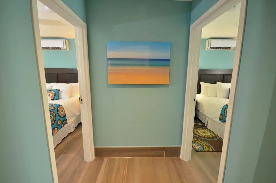 Two-bedroom suite hallway at Royal St. Kitts Hotel showing doorways to two bedrooms with white beds.
