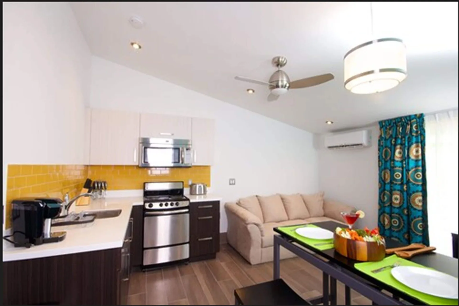 Two-bedroom suite kitchen and lounge at Royal St. Kitts Hotel with dining setup and sofa by the window.