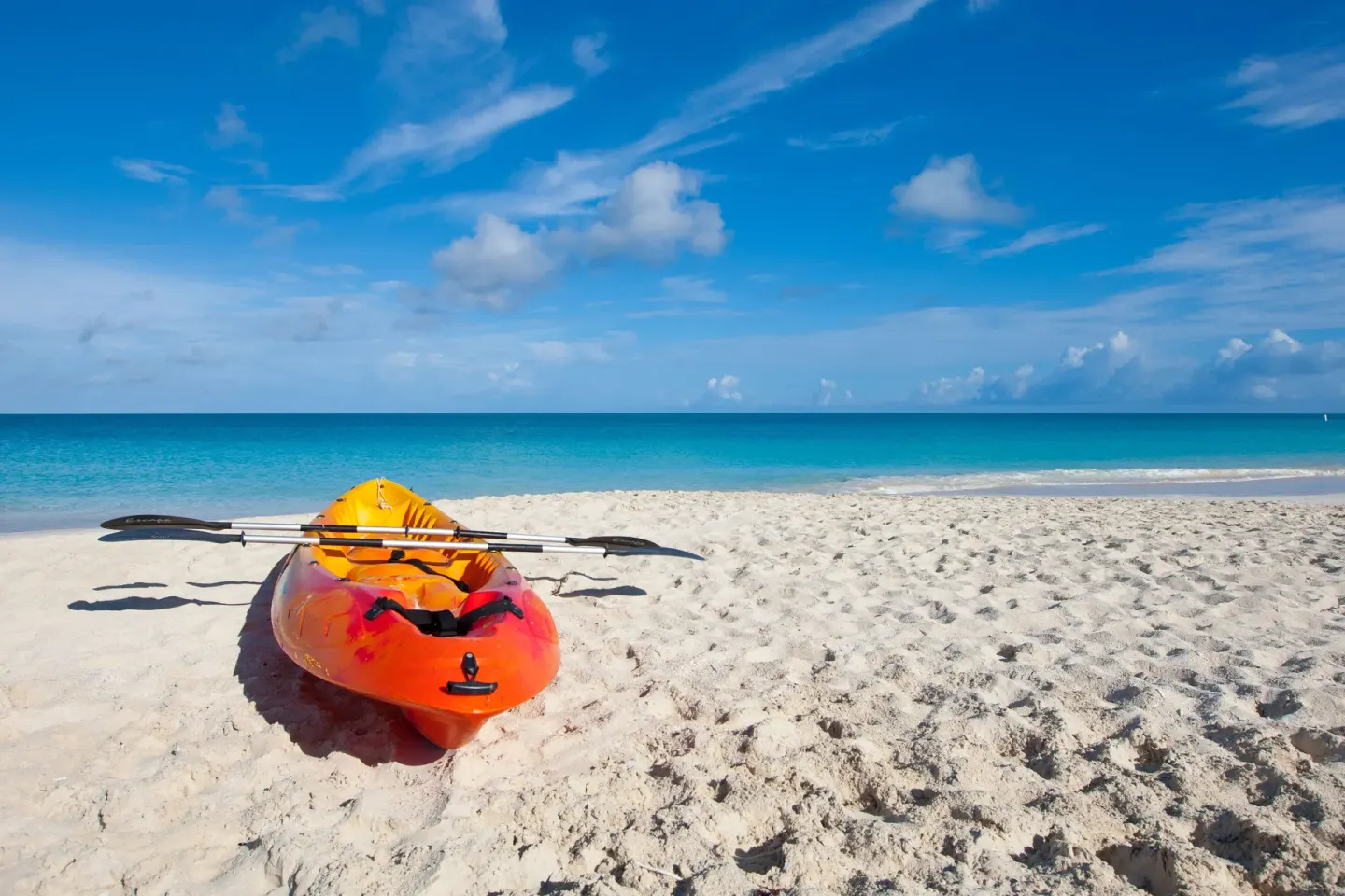 Orange kayak with paddles on the beach at Royal West Indies Resort beside turquoise water.
