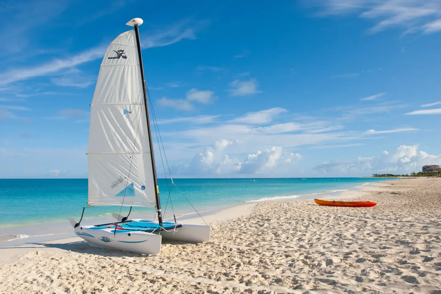 Small sailboat and kayak on the beach at Royal West Indies Resort with turquoise sea beyond.