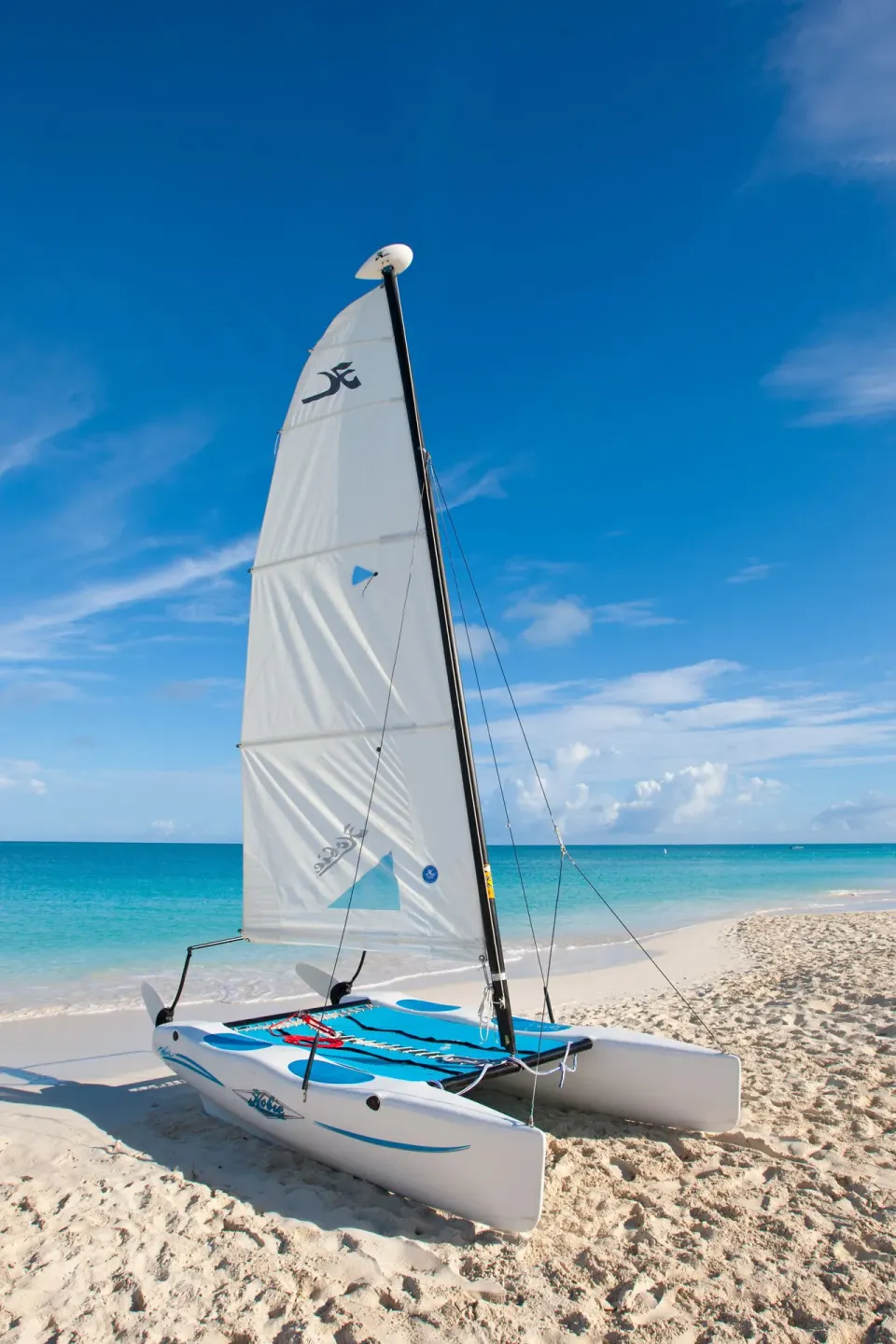 White sailboat on the sand at Royal West Indies Resort with the ocean and blue sky behind it.