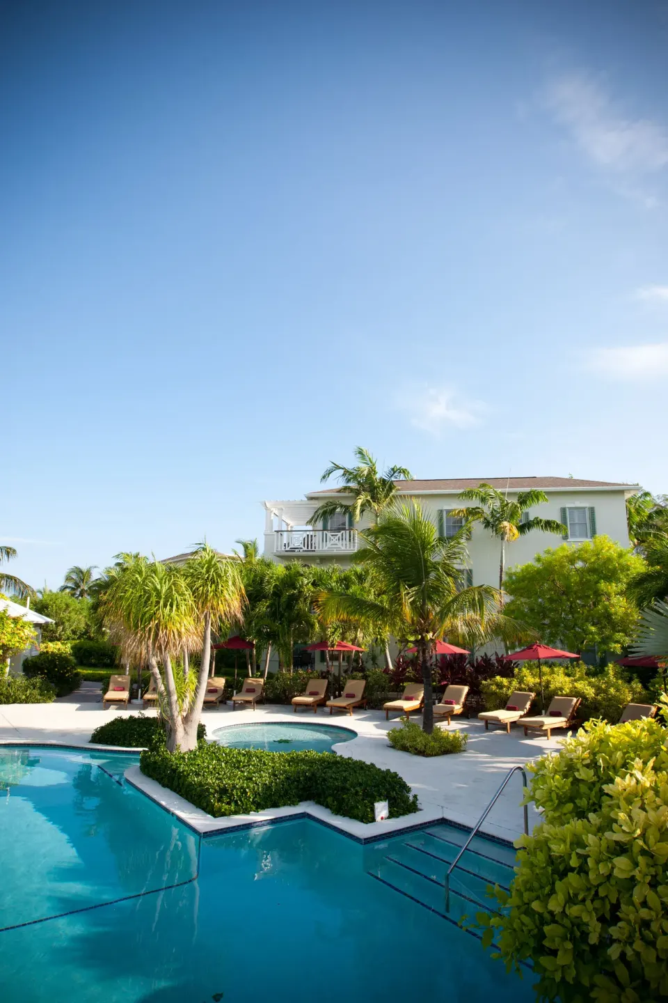 Pool terrace with loungers, umbrellas, palms, and resort building at Royal West Indies Resort.