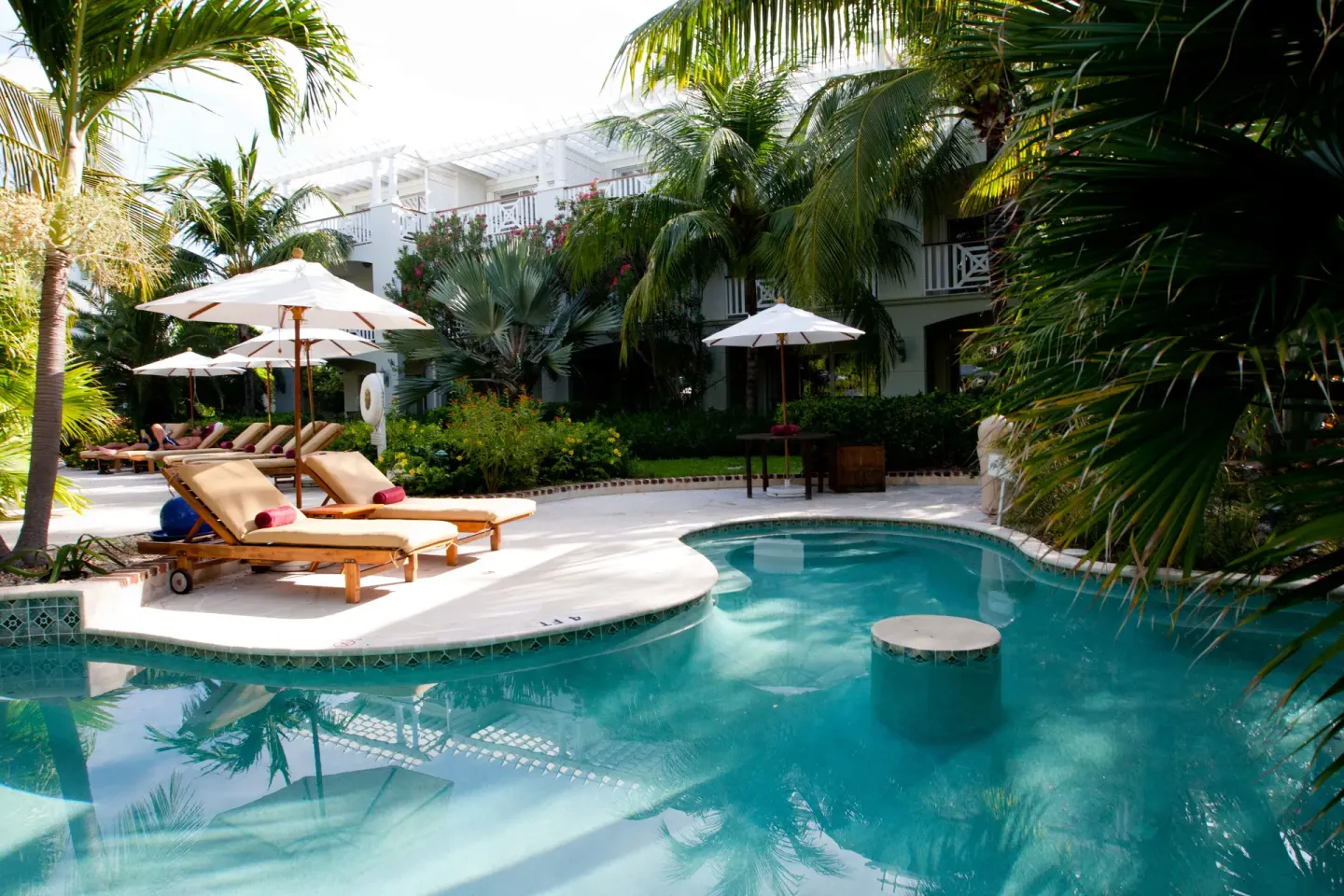 Poolside loungers and umbrellas beside tropical gardens at Royal West Indies Resort.