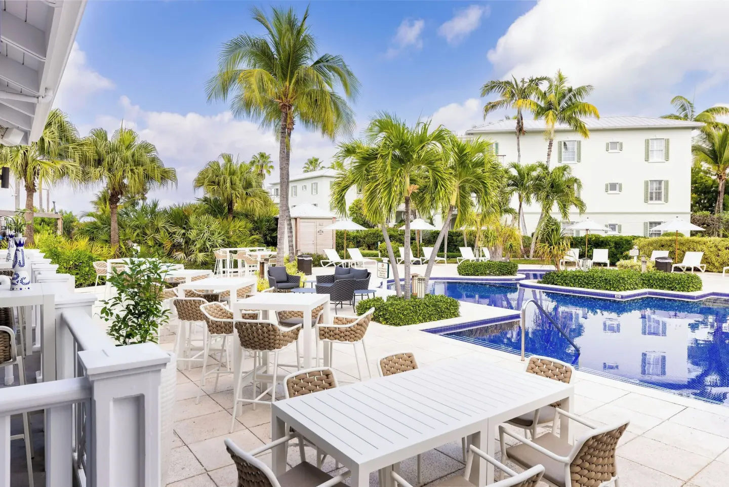 Poolside patio tables and palm trees beside the pool at Royal West Indies Resort.