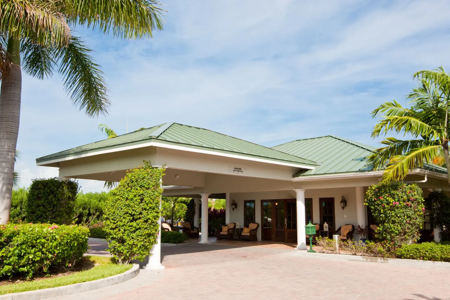Resort entrance with green roof, columns, and palms at Royal West Indies Resort.