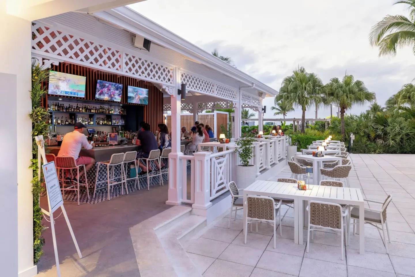 Open-air bar and patio seating at Royal West Indies Resort with guests at the counter.