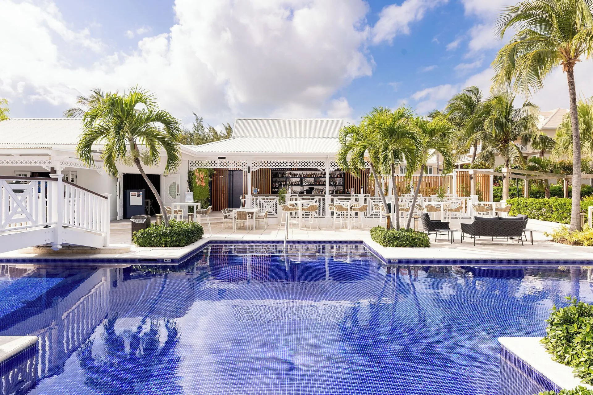 Blue-tiled pool facing an open-air bar and seating at Royal West Indies Resort.