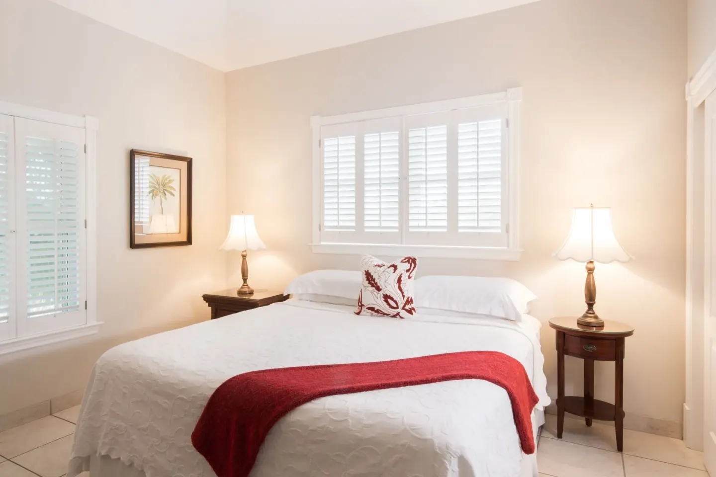 One bedroom garden view condo bedroom with white bed and red throw at Royal West Indies Resort.