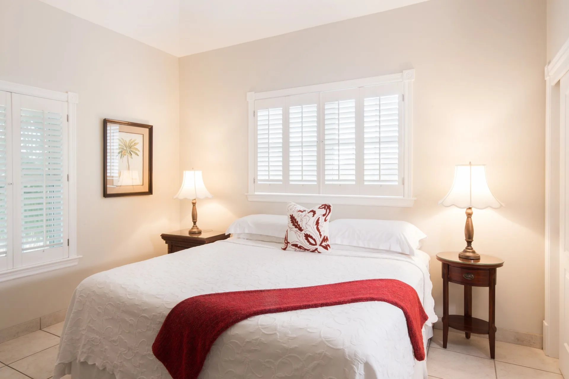 One bedroom garden view condo bedroom with white bed and red throw at Royal West Indies Resort.